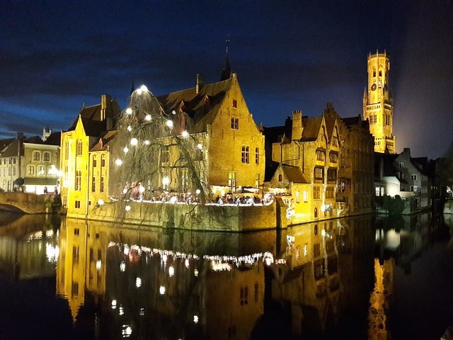 vista notturna di Bruges con il Rozenhoedkaai e la torre pendente Beffroi illuminati